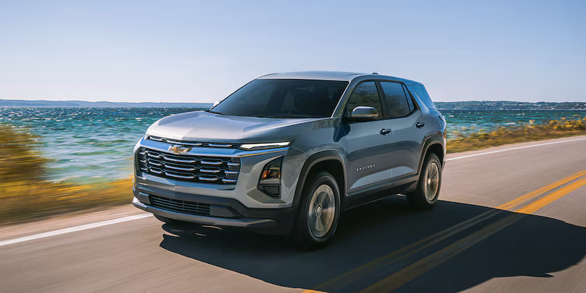 Silver Chevrolet Equinox driving along a coastal road